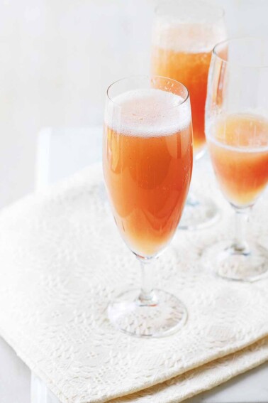 Three champagne flutes filled with classic bellini on a napkin.