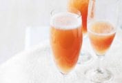 Three champagne flutes filled with classic bellini on a napkin.