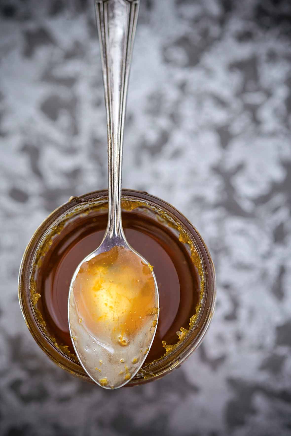 A jar of Meyer lemon syrup with a spoon resting on top.