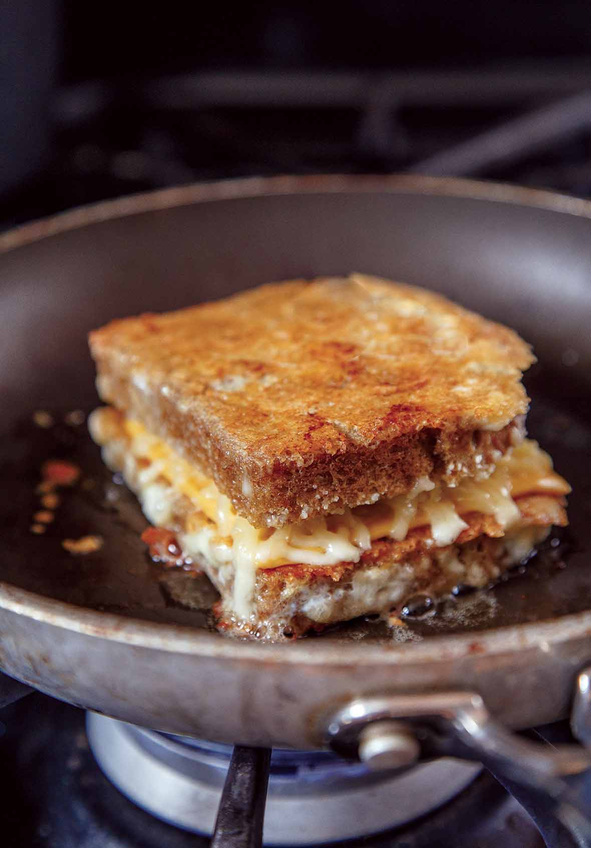 A cheese-crusted grilled cheese that is layered top and bottom with crispy Parmesan cheese in a skillet