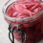 A jar full of pickled red onions sitting on a counter