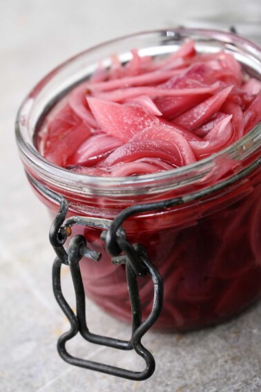 A jar full of pickled red onions sitting on a counter
