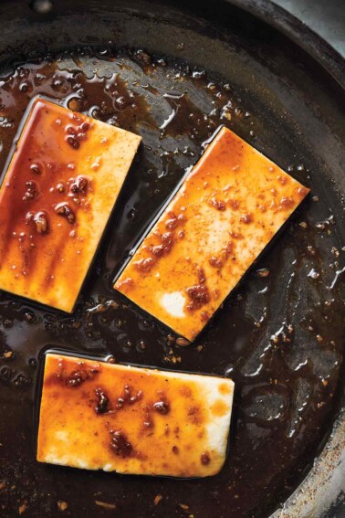 Three portions of glazed tofu in a skillet