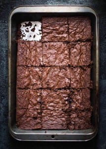 A metal baking pan of gluten free brownies with one piece missing