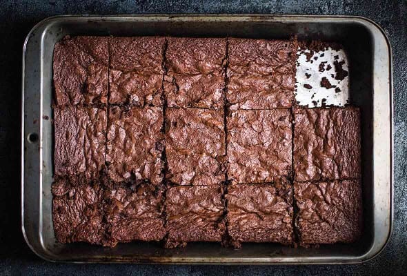 A metal baking pan of gluten free brownies with one piece missing