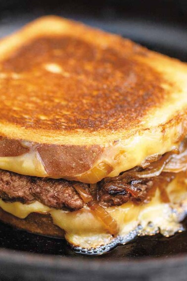 A patty melt sandwich filled with ground beef, caramelized onions and cheese.