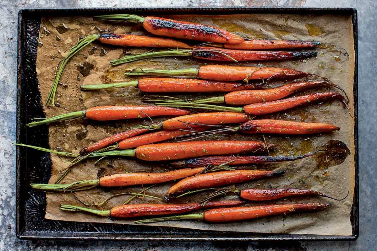 A bunch of roasted sweet and spicy carrots on a parchment-lined baking sheet.