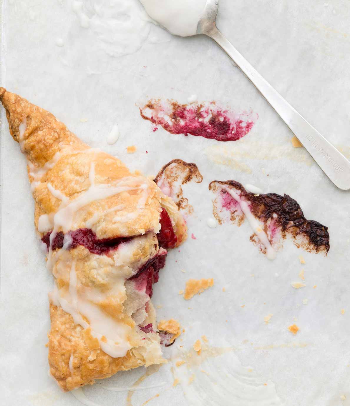 A fruit-filled Puff Pastry Turnover with a corner bitten off and a spoon resting above the pastry.