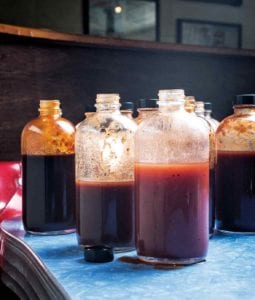 Several open glass bottles of barbecue sauces, including a vinegar barbecue sauce.