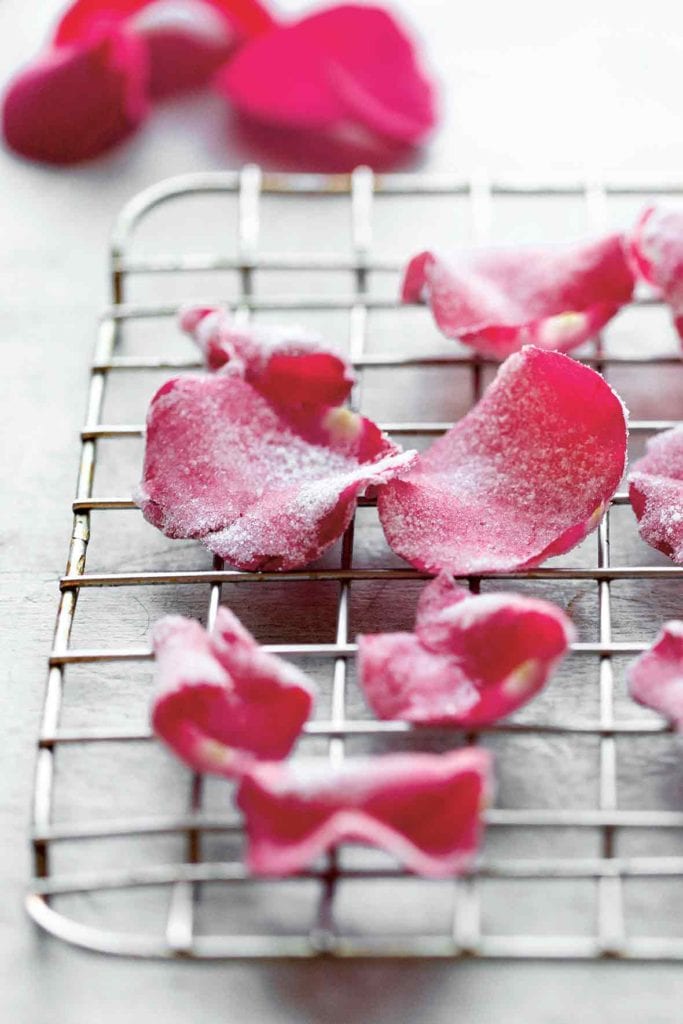 Several candied rose petals on a wire rack.