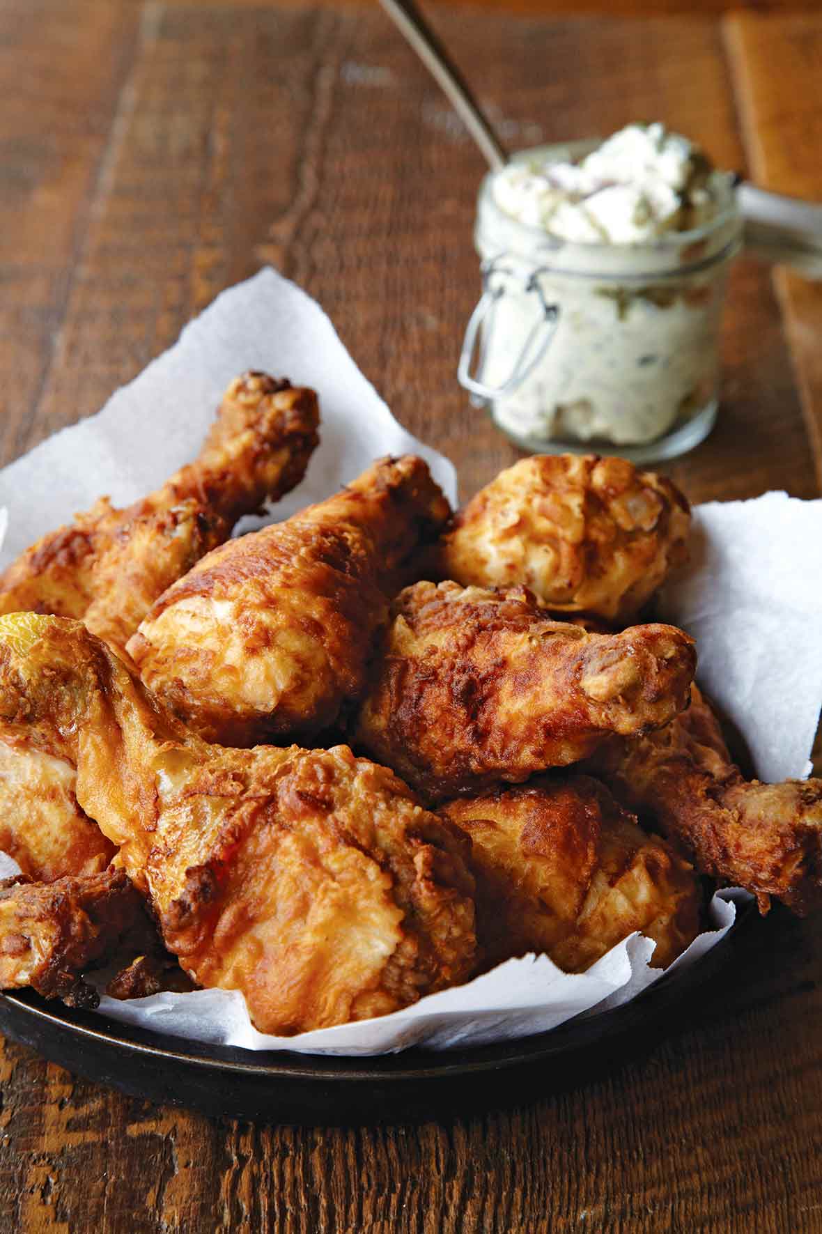 A platter of Nashville hot fried chicken with a jar of whipped butter in the background.