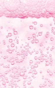 A closeup of pink beer bubbles in a glass.