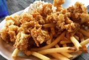 A paper basket filled with golden fried clams and fries