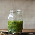 Mason jar of Greek marinade with parsley, oregano, thyme, rosemary, basil on a cutting board
