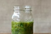 Mason jar of Greek marinade with parsley, oregano, thyme, rosemary, basil on a cutting board
