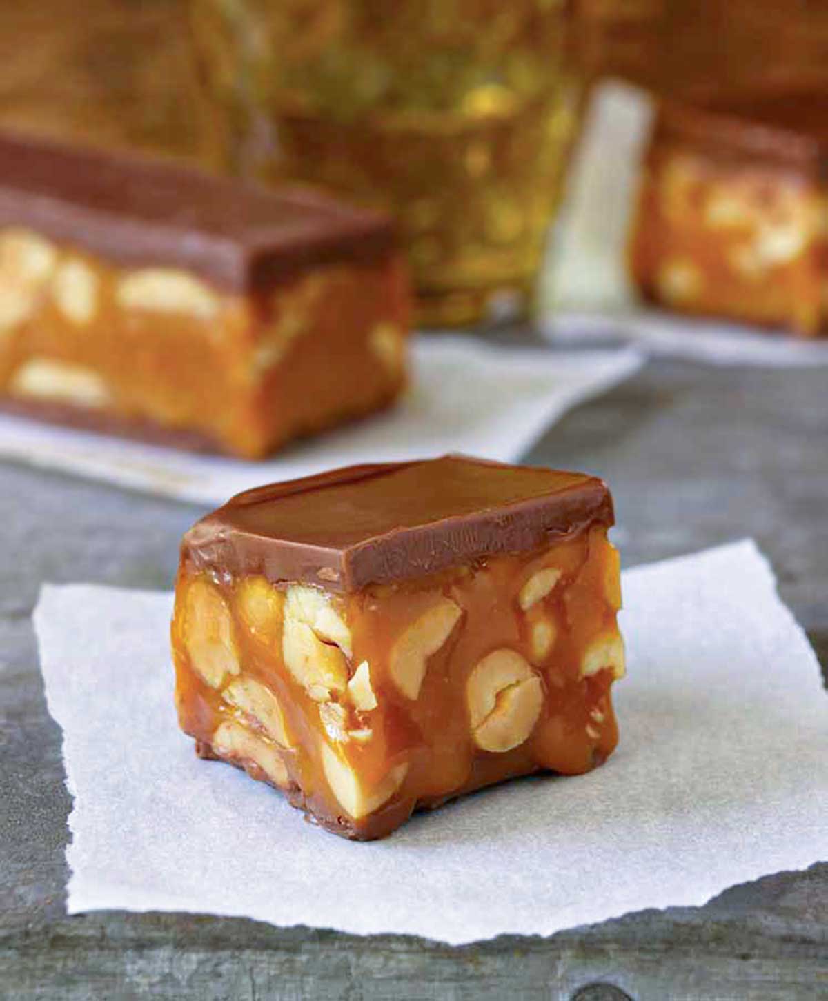 A square piece of homemade snickers bar on a piece of parchment.