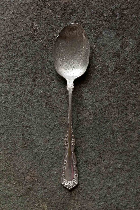 An old, worn spoon on a stone background.