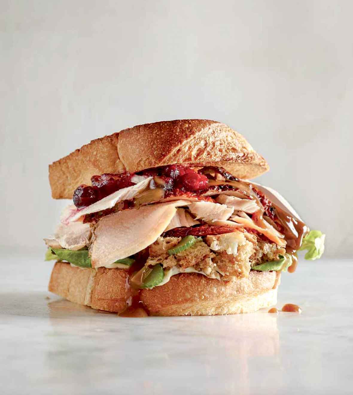 A leftover turkey cranberry sandwich on a white surface.