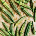 Pieces of roasted okra with spices on a parchment-lined baking sheet.