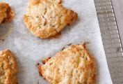 Six apple and white cheddar scones on a piece of parchment on top of a cooling rack.