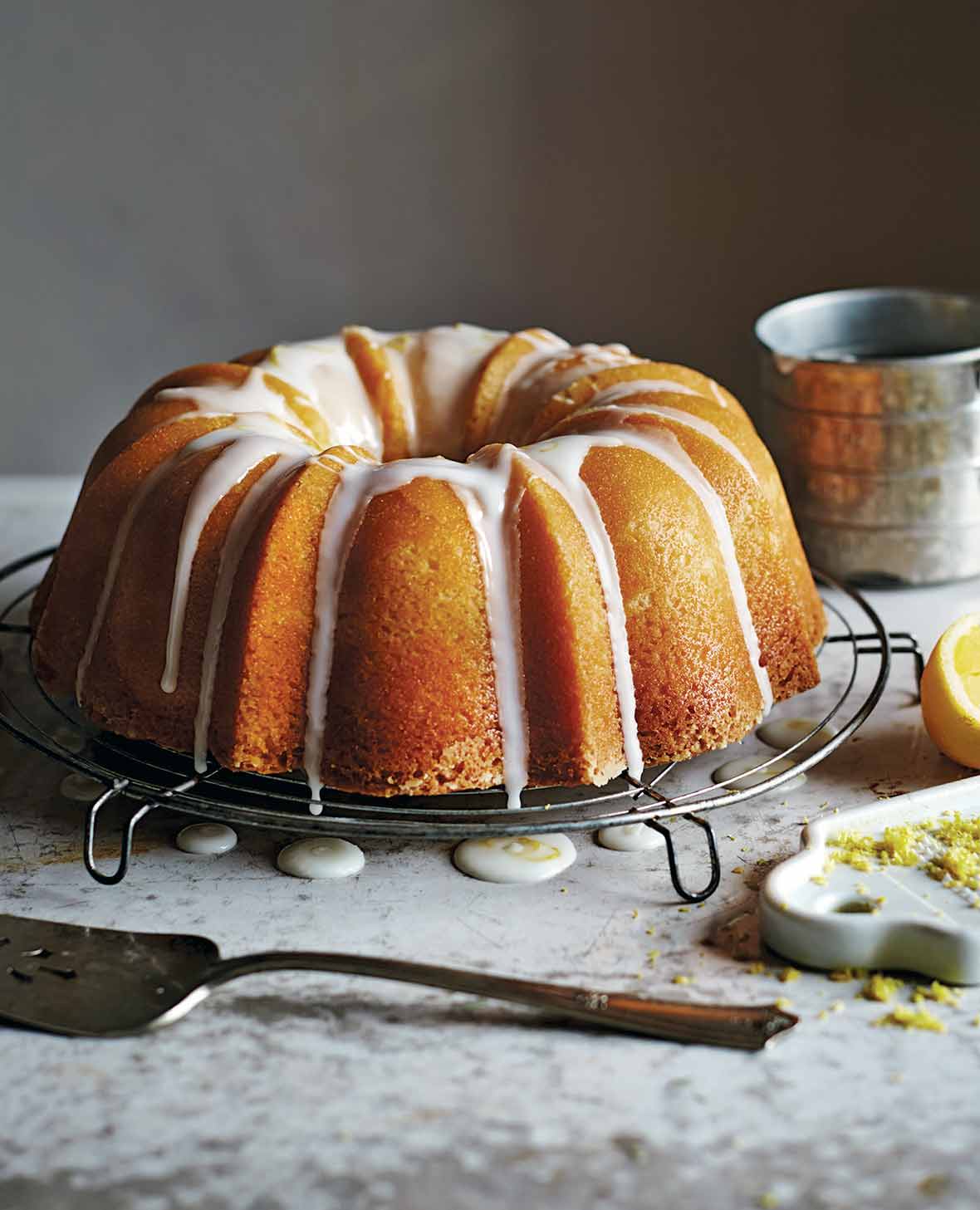 A lemon pound cake resting on a round wire rack, drizzled with a white icing glaze