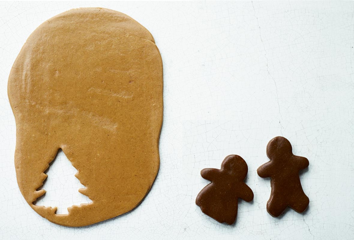 Pieces of light and dark gingerbread, with two people cut out of the dark, and a tree shape cut out of the light gingerbread.