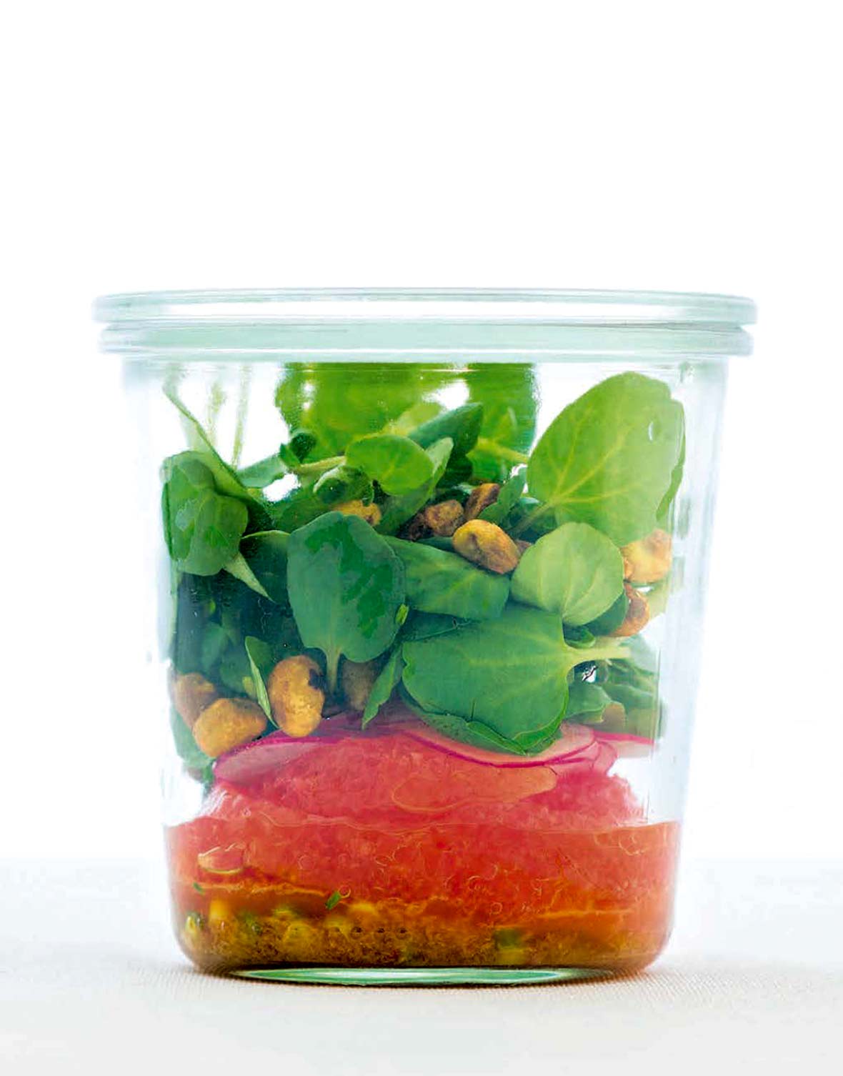 A grapefruit and watercress salad in a glass jar.