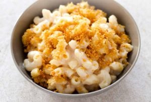 A grey bowl filled with baked mac and cheese topped with bread crumbs.