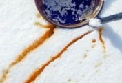 A bucket of maple syrup in the snow with streaks of maple syrup snow nearby