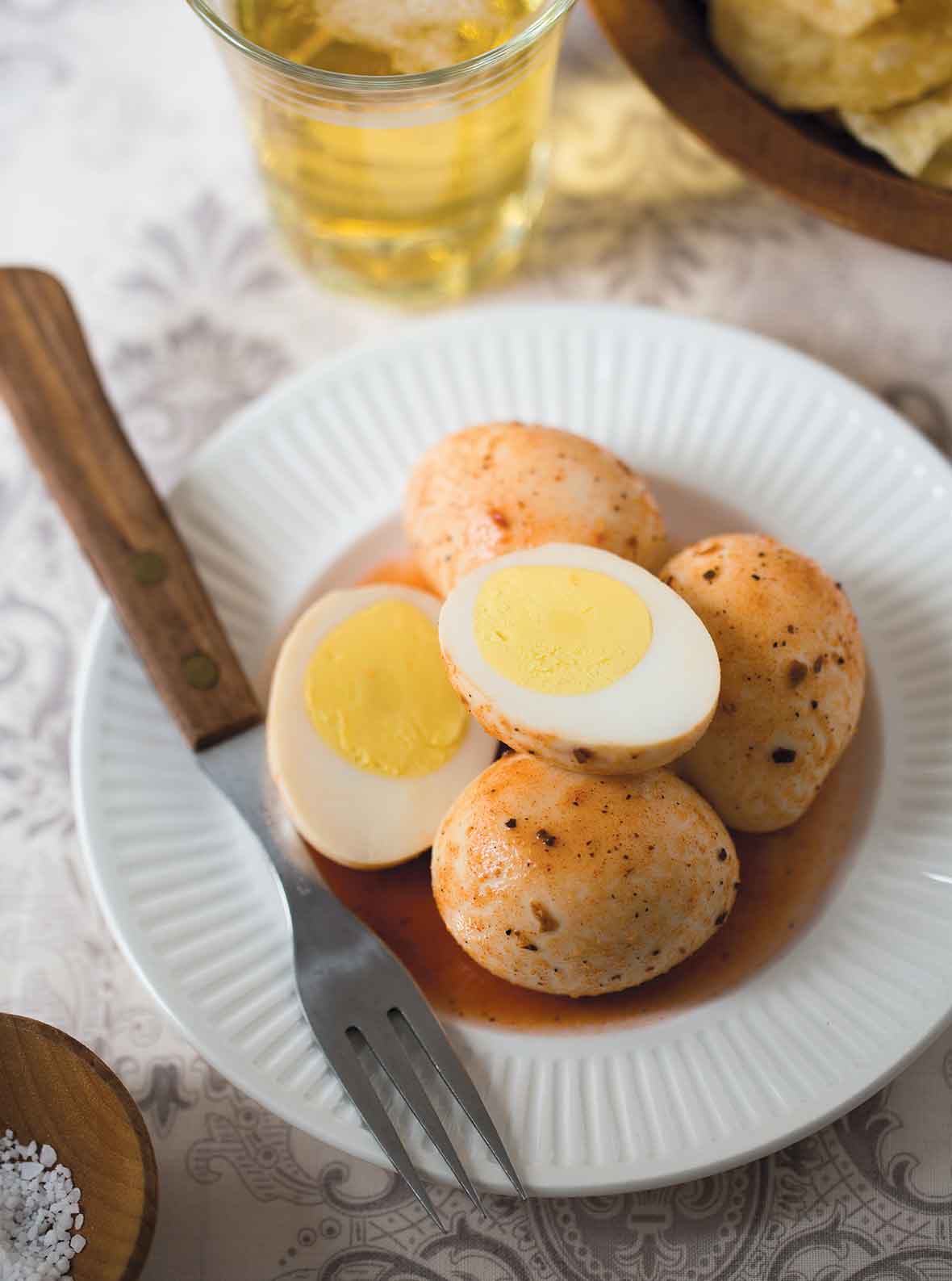 A white plate topped with four Cajun pickled eggs, one of which is cut in half. A fork rests on the plate.