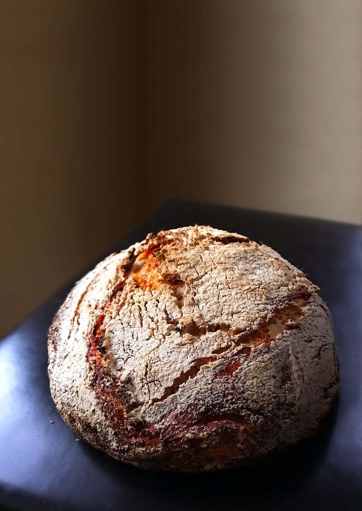 A round loaf of Jim Lahey's no-knead bread, dusted with flour on a leather chair
