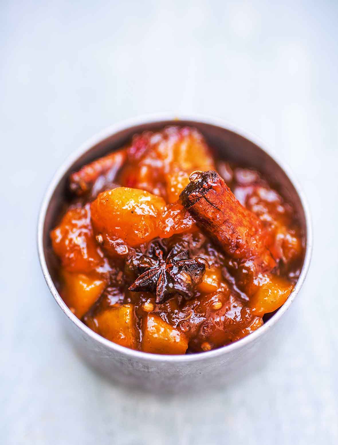 A bowl filled with mango chutney, with visible pieces of cinnamon and star anise