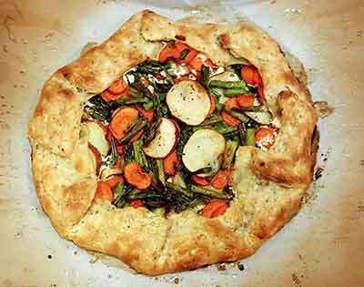 Colorfrul Vegetable Galette baked and on parchment paper cooling.