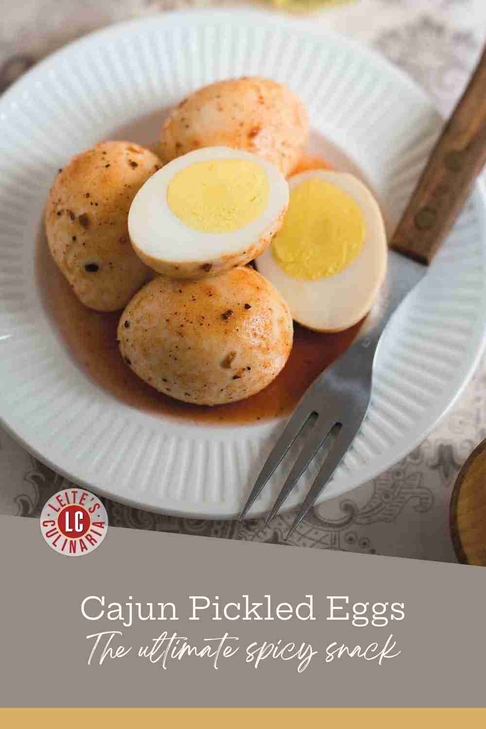 Halved hard-boiled egg showing a bright yellow yolk, coated in red Cajun spices and vinegar brine.