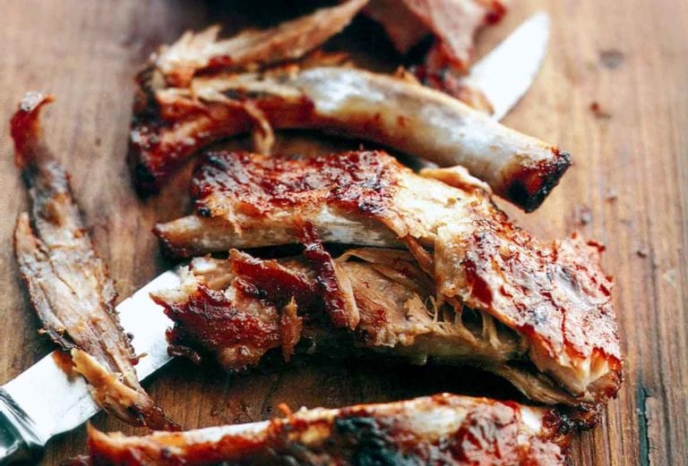 A slab of fall-off-the-bone baby back ribs with a knife cutting them into individual ribs.
