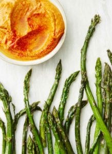 Tips of roasted asparagus with romesco sauce in a bowl nearby.