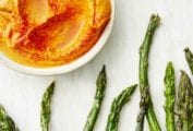 Tips of roasted asparagus with romesco sauce in a bowl nearby.