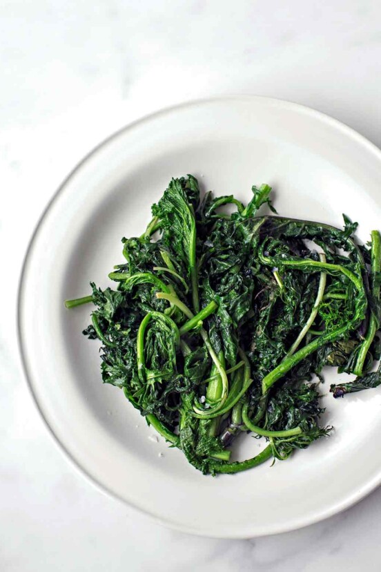 A pile of charred greens--kale and spinach--on a white plate.