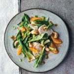 Asian chicken salad with oranges and cashews on a grey plate.