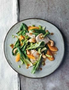 Asian chicken salad with oranges and cashews on a grey plate.