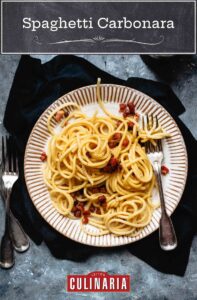 En skål fylld med spaghetti carbonara, toppad med nyriven parmesan.