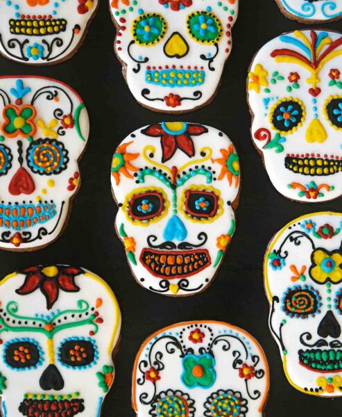 An assortment of day of the dead cookies on a dark background.