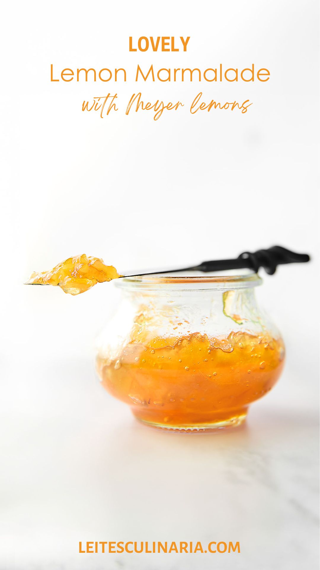 A small jam jar filled with Meyer lemon marmalade. Resting on top is a knife with a dollop of marmalade on top.