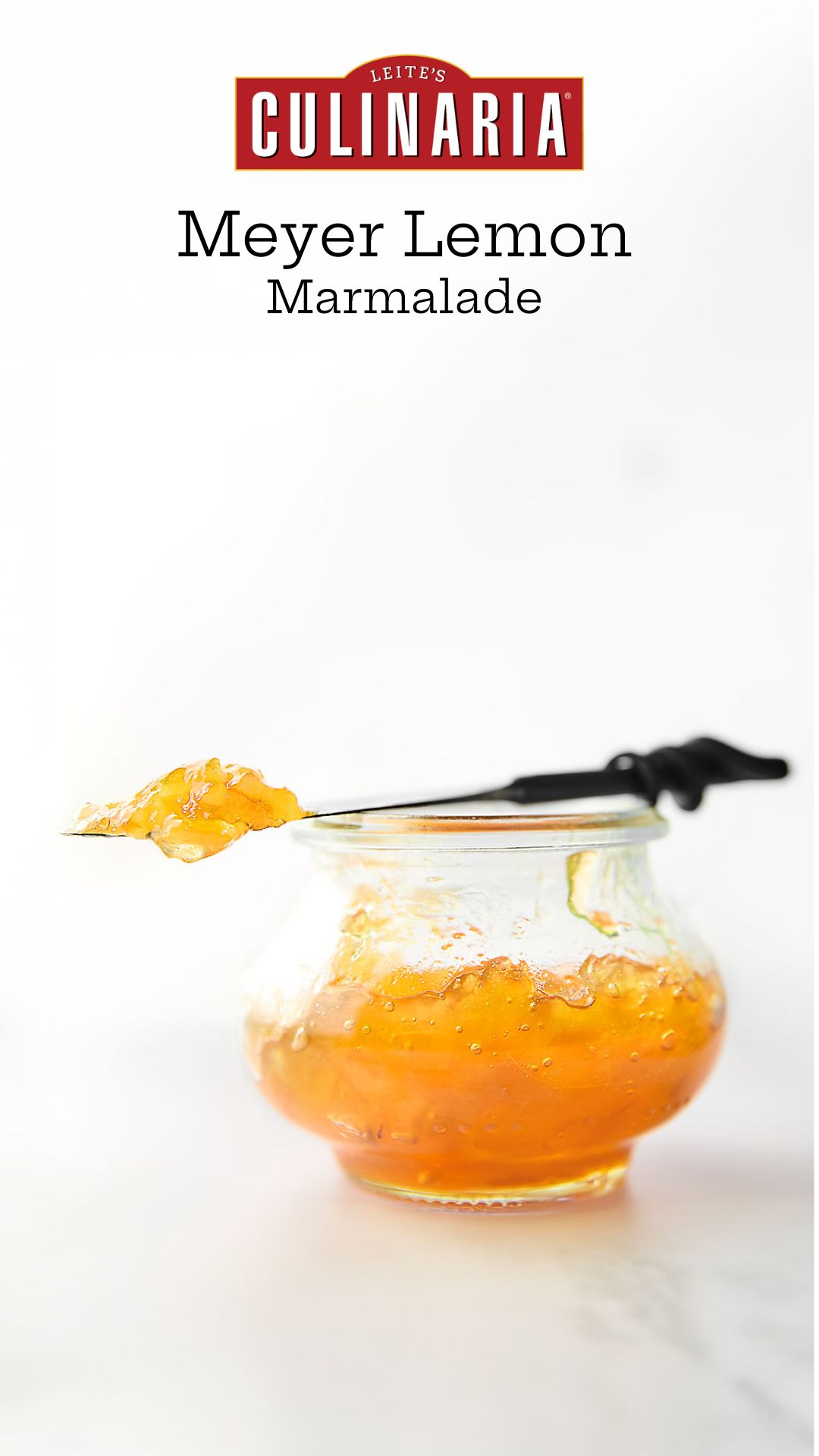 A small jam jar filled with Meyer lemon marmalade. Resting on top is a knife with a dollop of marmalade on top.