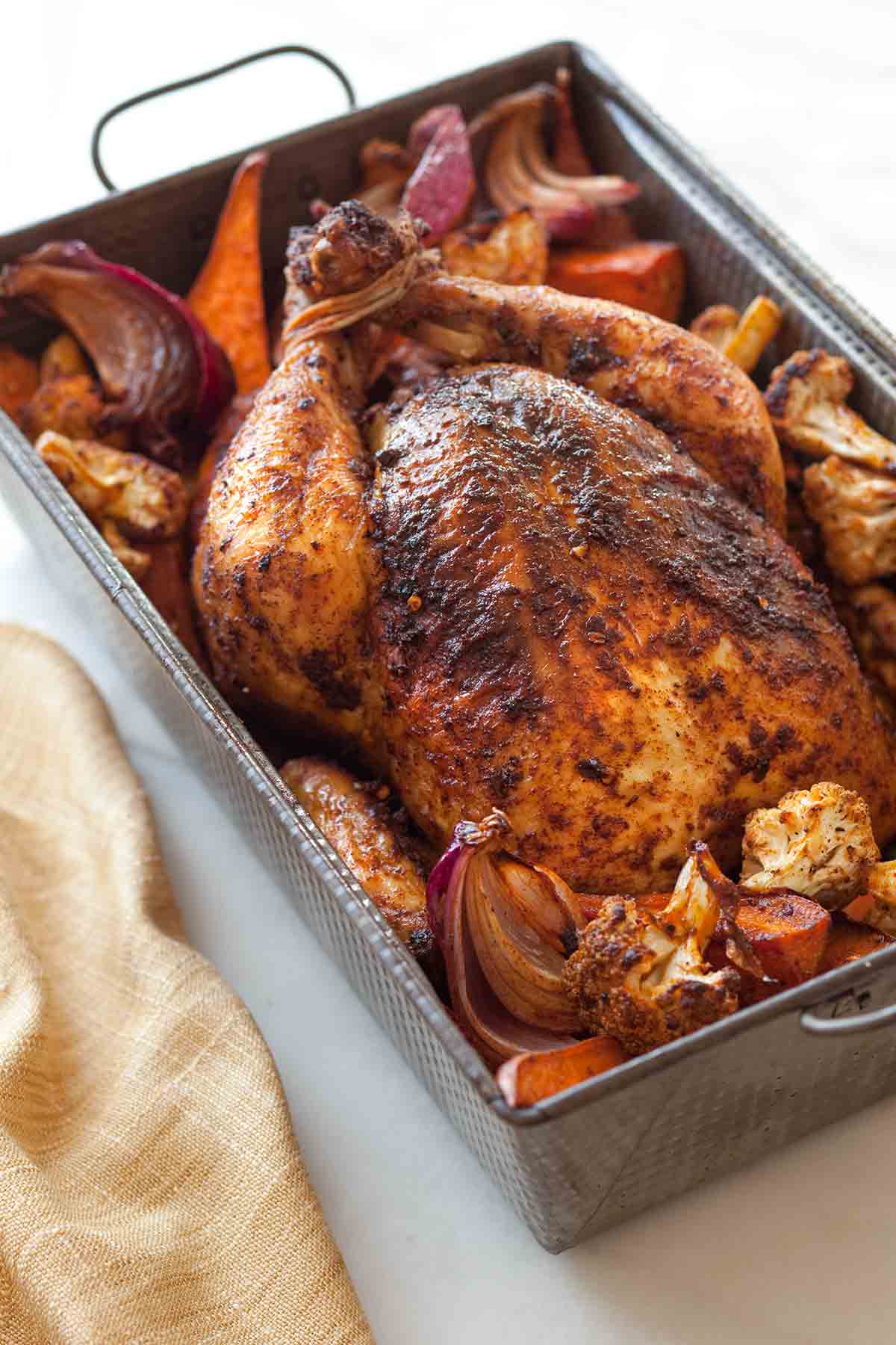 A deep roasting pan filled with roast chicken and vegetables