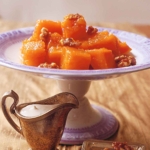 A cake stand of syrup-soaked pumpkin cubes topped with nuts.