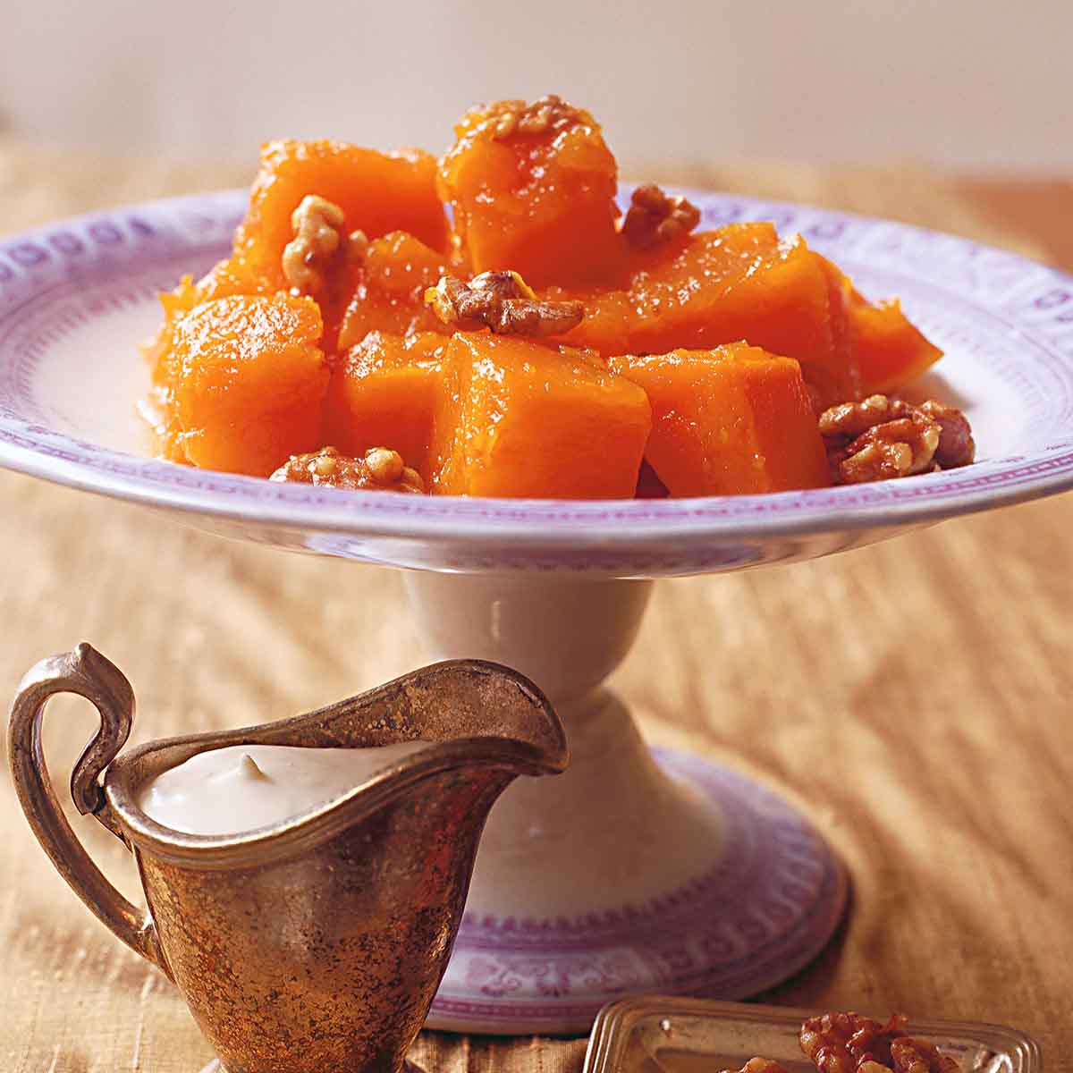 A cake stand of syrup-soaked pumpkin cubes topped with nuts.