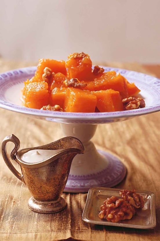 A platter with cubed pumpkin cooked slowly in sugar syrup topped with walnuts.