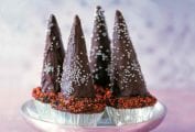 Four cupcakes with chocolate icing, topped with chocolate wizard hats.