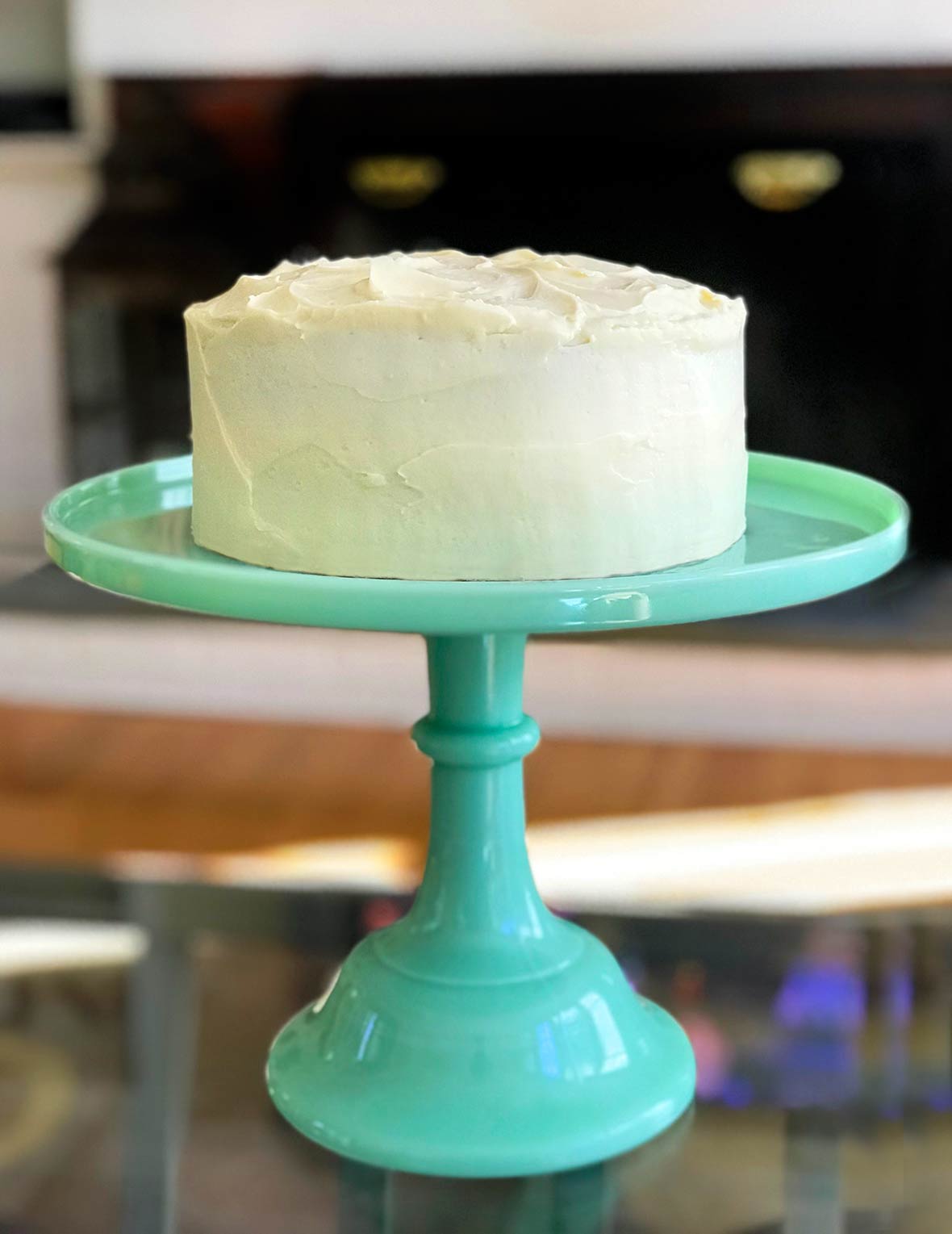 A pumpkin cake with maple-cream cheese frosting on a teal cake stand.